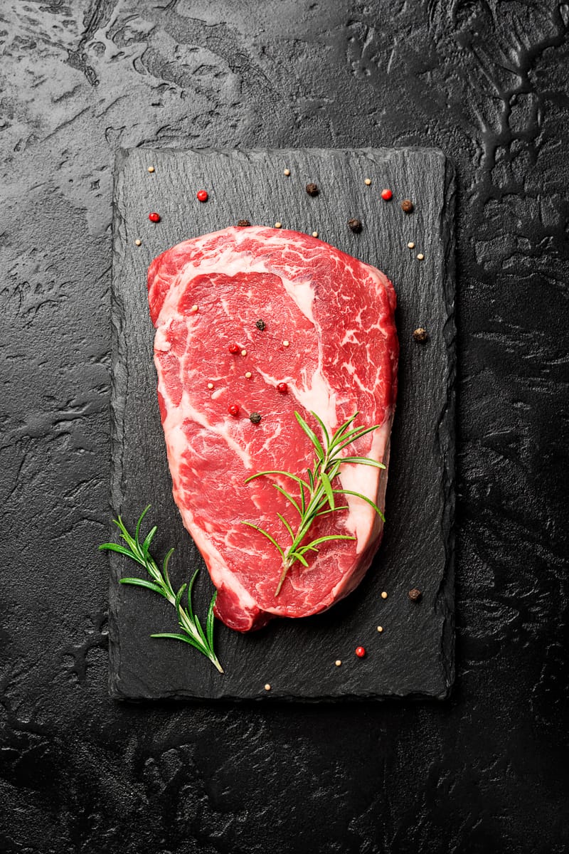 Raw beef steak with rosemary on a slate board