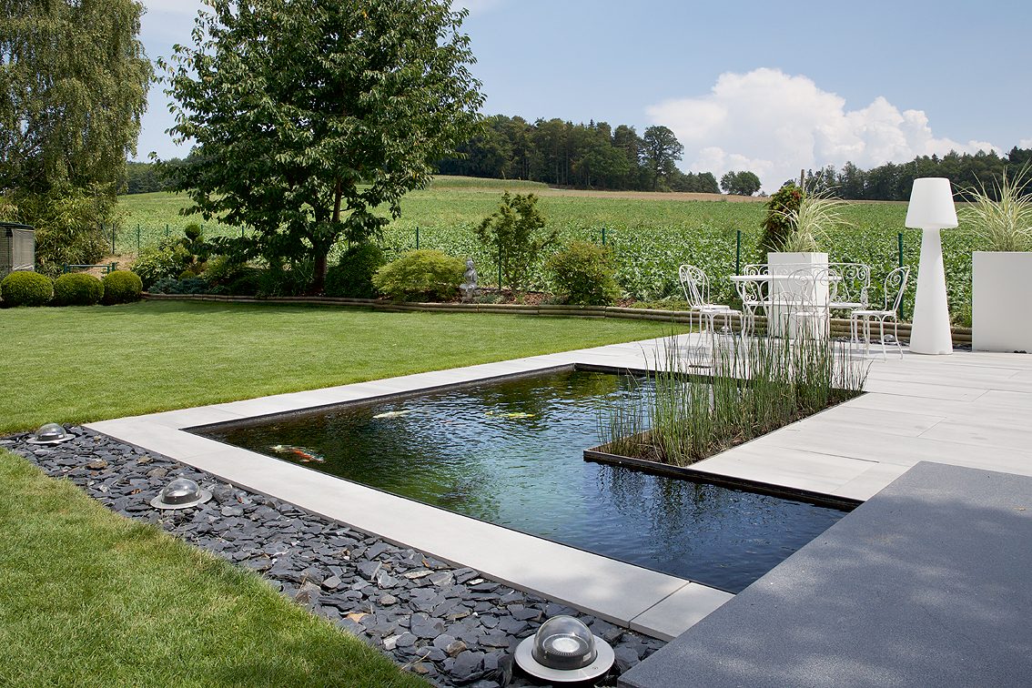 The L-shaped natural pool seen from the lawn, open landscape behind