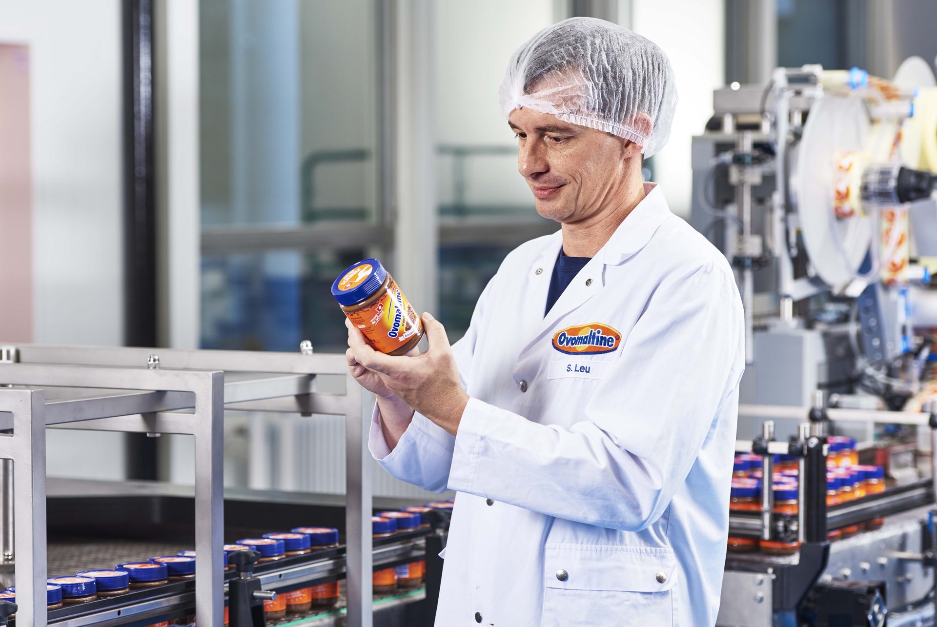 Employee checking an Ovomaltine tin on the production line