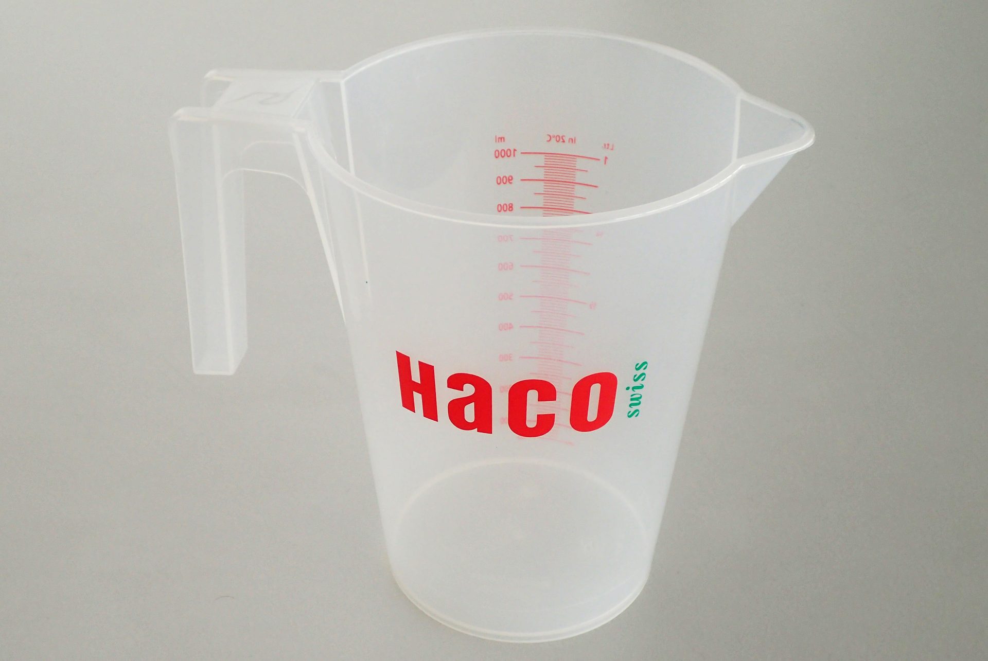 Plastic measuring jug with printed HACO logo and red scale