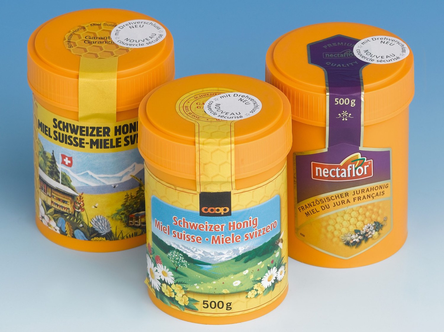 Plastic honey tins with orange lids and various labels