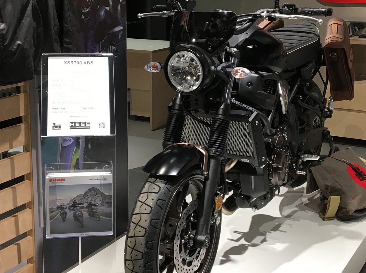 Infoständer mit Preisblatt und Prospektfach neben einem Motorrad im Showroom