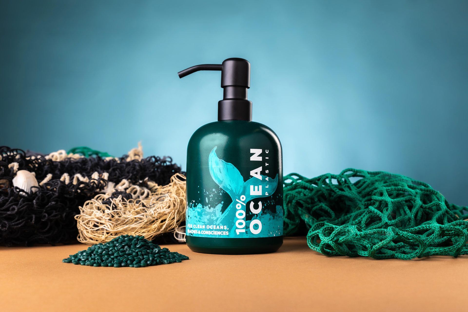 Seifenspender aus Ocean Plastic mit Metallpumpe, daneben Rezyklat-Granulat und ein Fischernetz