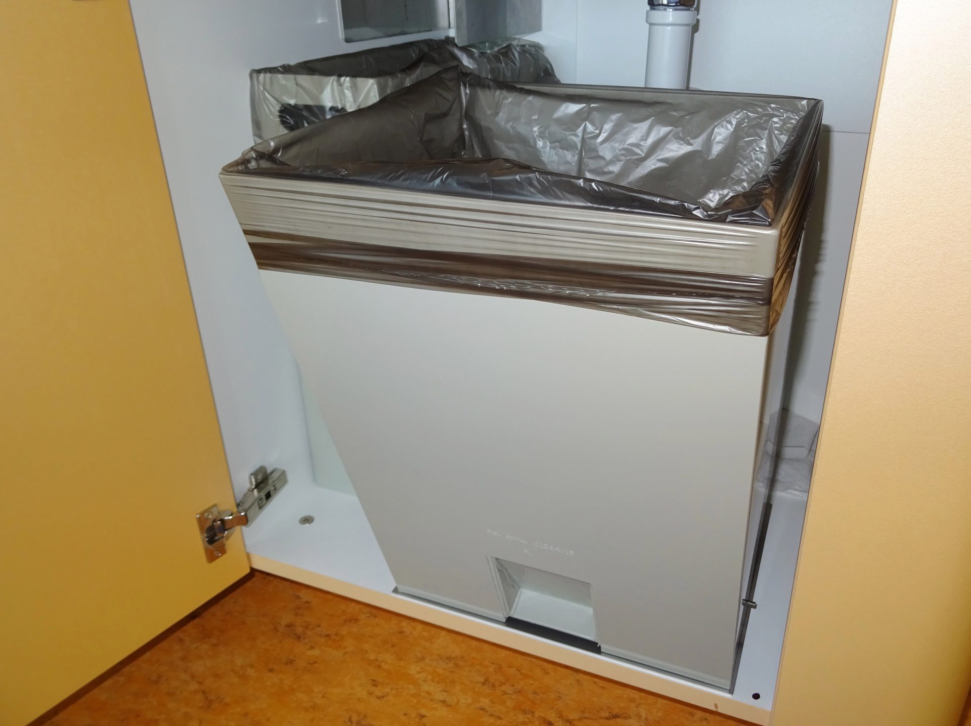 Kippkübel mit eingehängtem Abfallsack im geöffneten Einbauschrank